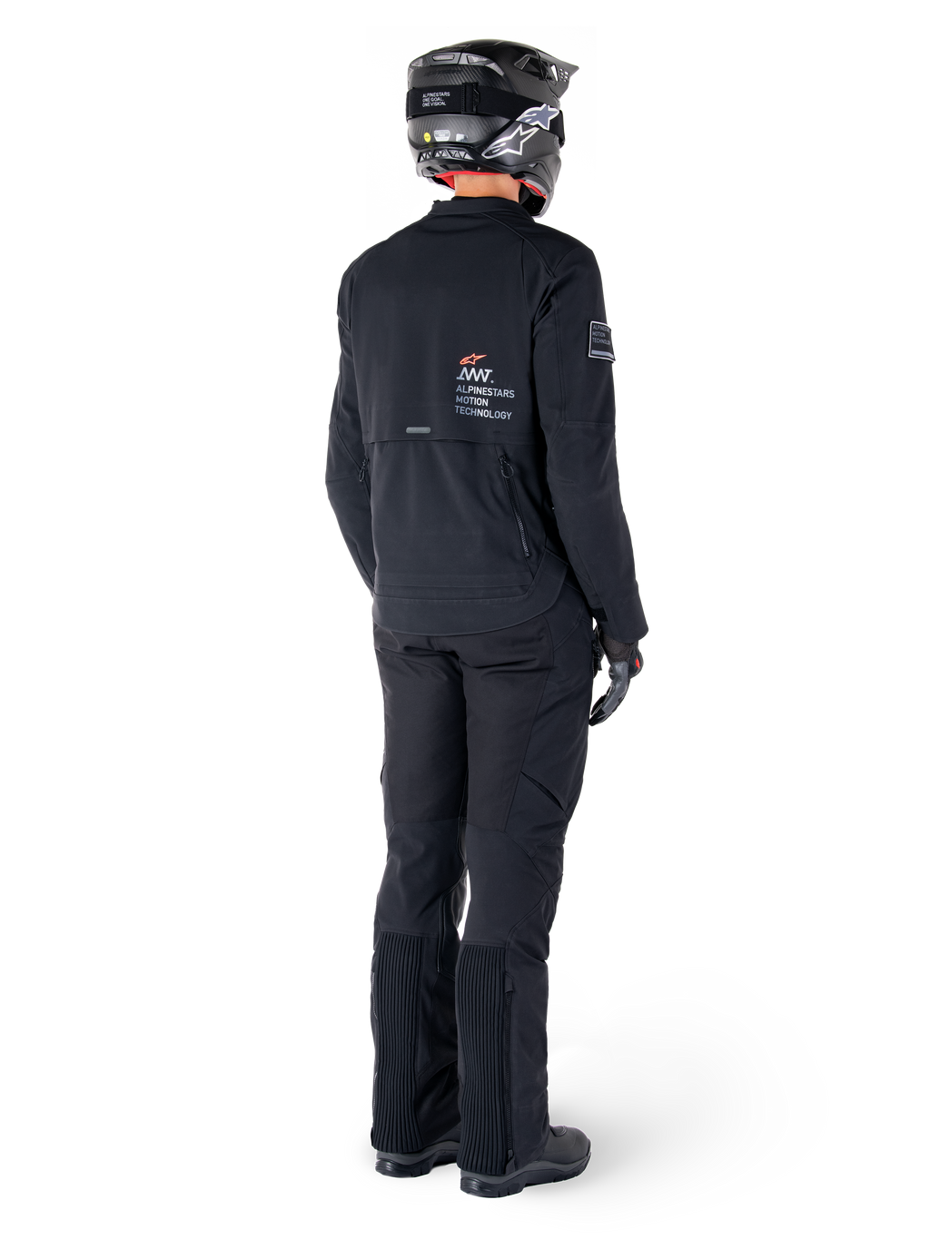 Alpinestars AMT-8 Stretch Drystar® XF jakke, sort, set bagfra af en kører iført jakken med matchende sorte bukser og en sort hjelm, med 'Alpinestars Motion Technology' branding på ryggen, teknisk strækmateriale til adventure-motorcykelkørsel