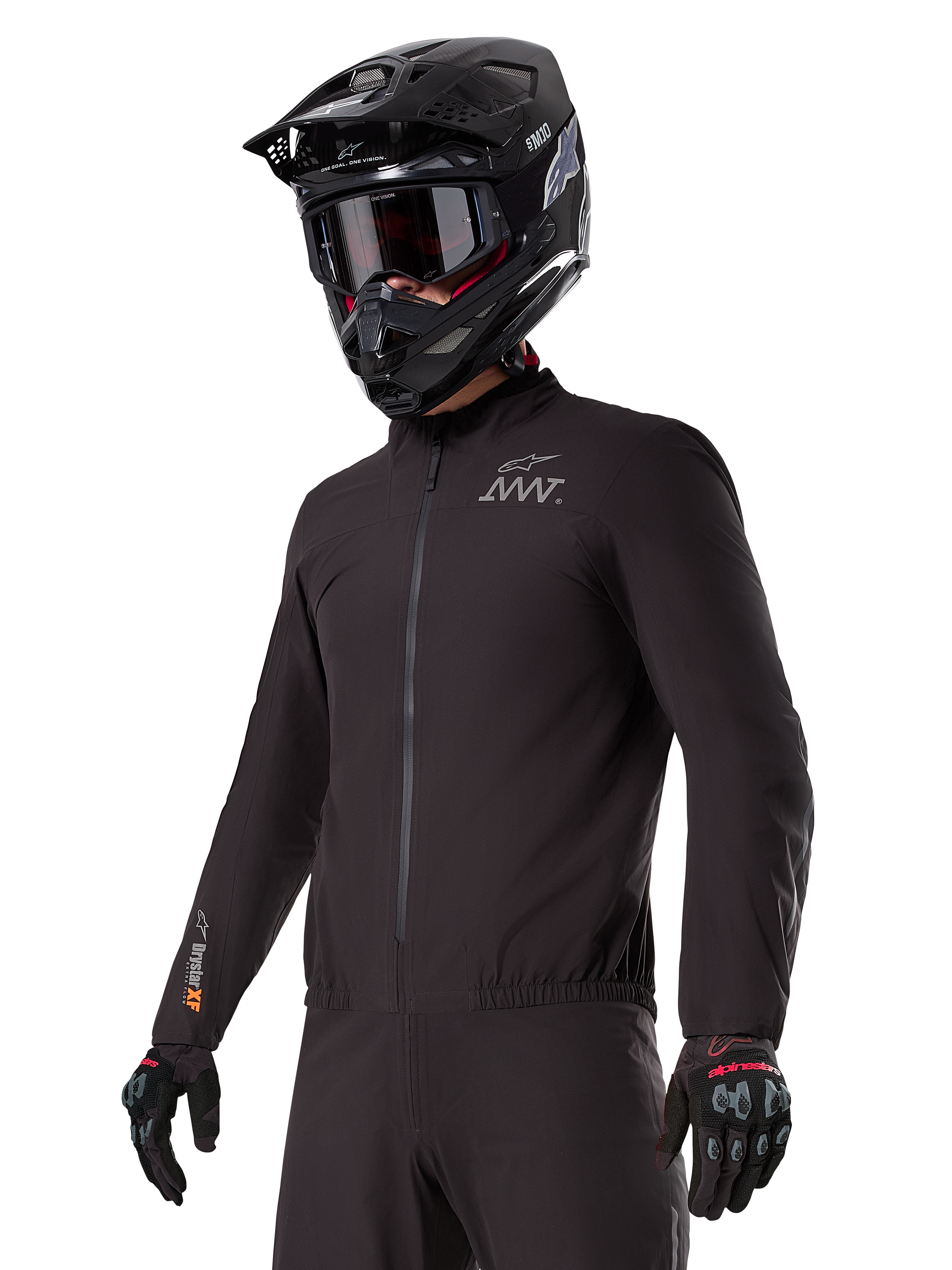 Motorcyklist iført Alpinestars AMT-8 Stretch Drystar® XF Liner, sort vindtæt og vandtæt strækjakke med AMT-logo på brystet og Drystar XF-branding på ærmet, kombineret med en sort adventure-hjelm og beskyttelseshandsker.