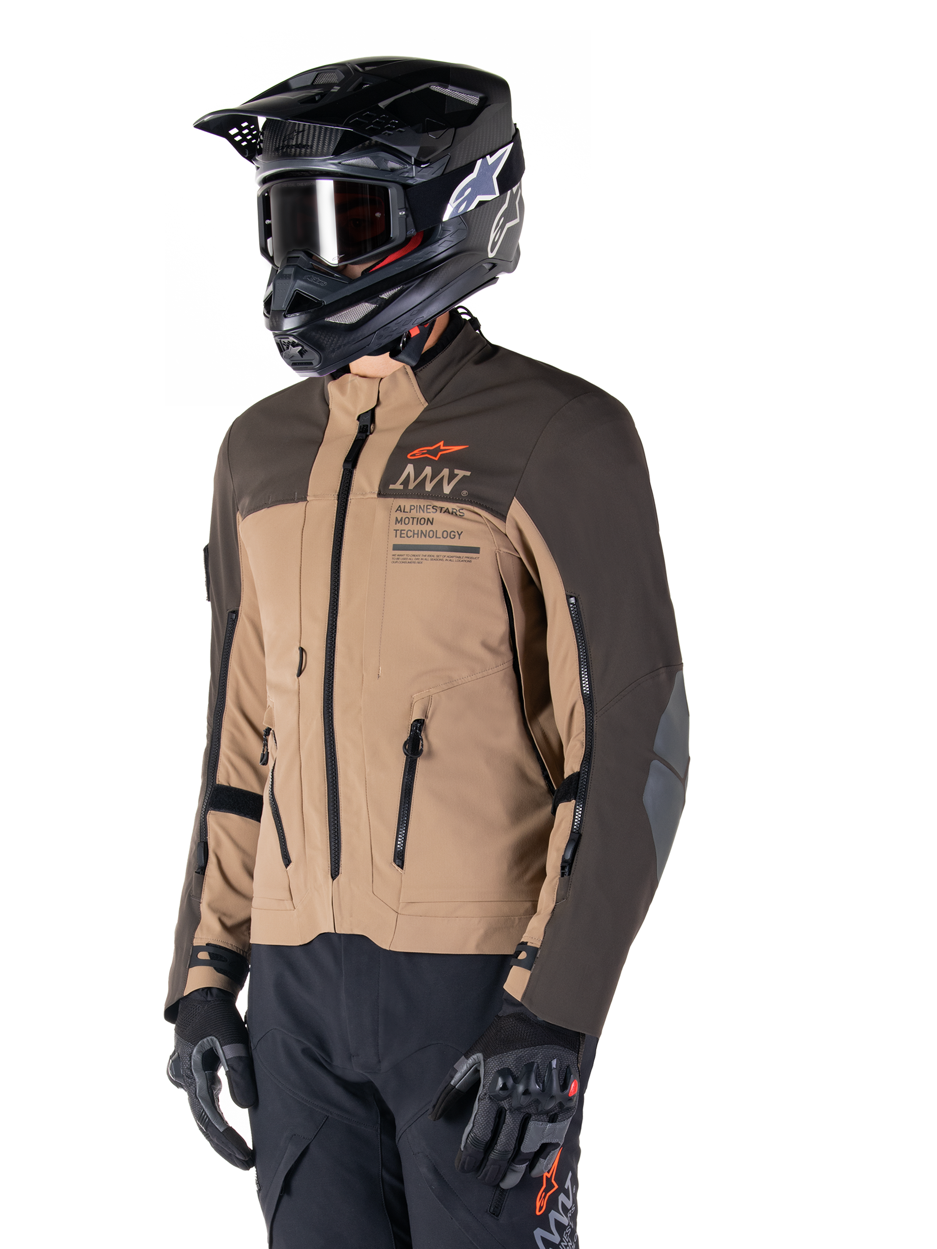 Alpinestars AMT-8 Stretch Drystar® XF Jakke, adventure motorcykeljakke, mørkebrun og mørk khaki, båret med en sort off-road hjelm og goggles, med Alpinestars Motion Technology-branding og lynlåslukkede ventilationsåbninger.