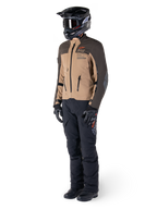Adventure-rytter iført komplet udstyr, Alpinestars AMT-8 Stretch Drystar® XF-jakke i mørkebrun og mørk khaki, kombineret med sorte adventure-bukser, sort hjelm, handsker og støvler, med orange AMT-branding og tekniske ventilationslynlåse til langdistance-touring