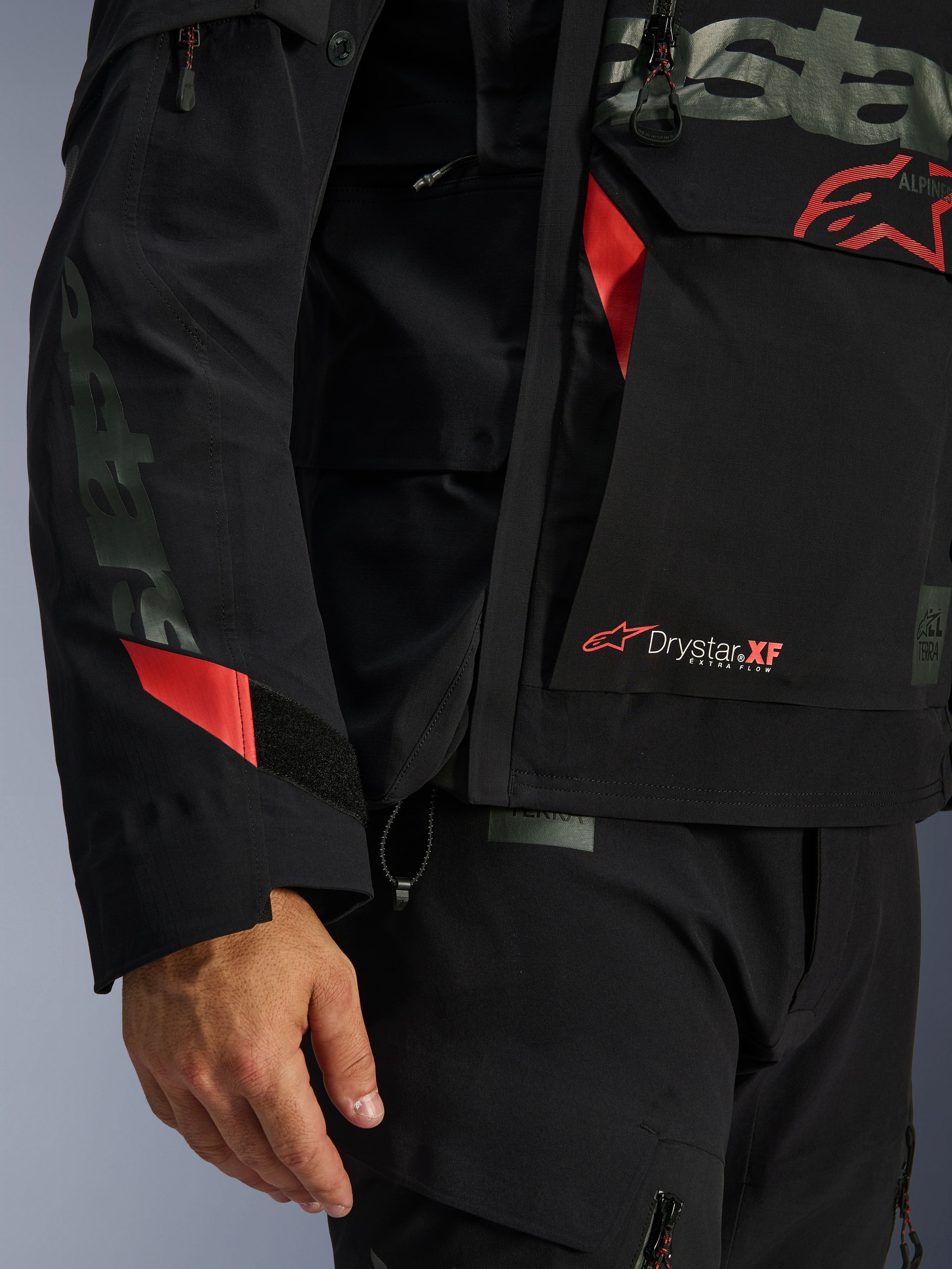 Alpinestars Halo Pro Drystar® XF lamineret jakke, motorcykeljakke, sort med røde detaljer, nærbillede med Drystar® XF-branding, teknisk lamineret skaltekstur og justerbare ærmedetaljer til adventure-kørsel