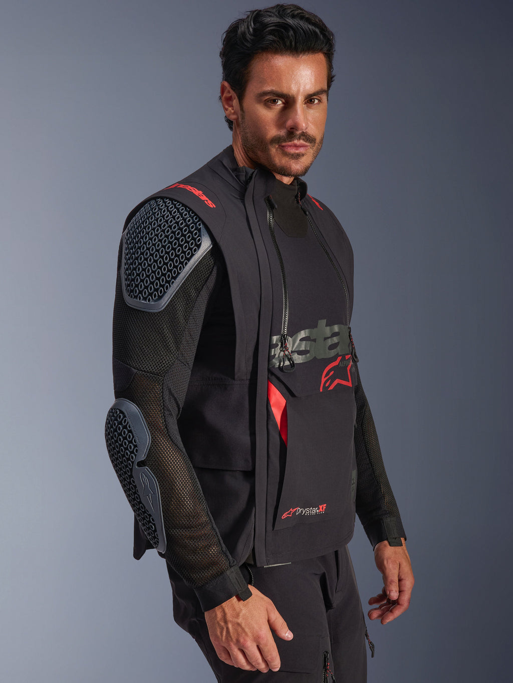 Alpinestars Halo Pro Drystar® XF lamineret jakke, Black og Dark Shadow, adventure-motorcykeljakke båret af model, modulær konfiguration med mesh-ærmer og integreret skulder- og albuebeskyttelse, røde logodetaljer og tekniske vandtætte lynlåse.