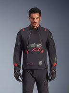 Alpinestars Halo Pro Drystar® XF lamineret jakke, adventure-motorcykeljakke, Black Dark Shadow med røde detaljer, mandlig model iført komplet teknisk udstyr inklusiv matchende handsker og bukser, set forfra der fremhæver modulære brystventilationspaneler og vandtæt konstruktion.