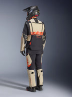 Alpinestars Halo Pro Drystar® XF lamineret jakke, Mastic Black, set bagfra af en kører iført den fulde adventure-motorcykeldragt med matchende bukser, sort adventure-hjelm og støvler, med et markant rødt Alpinestars-logo hen over ryggen.