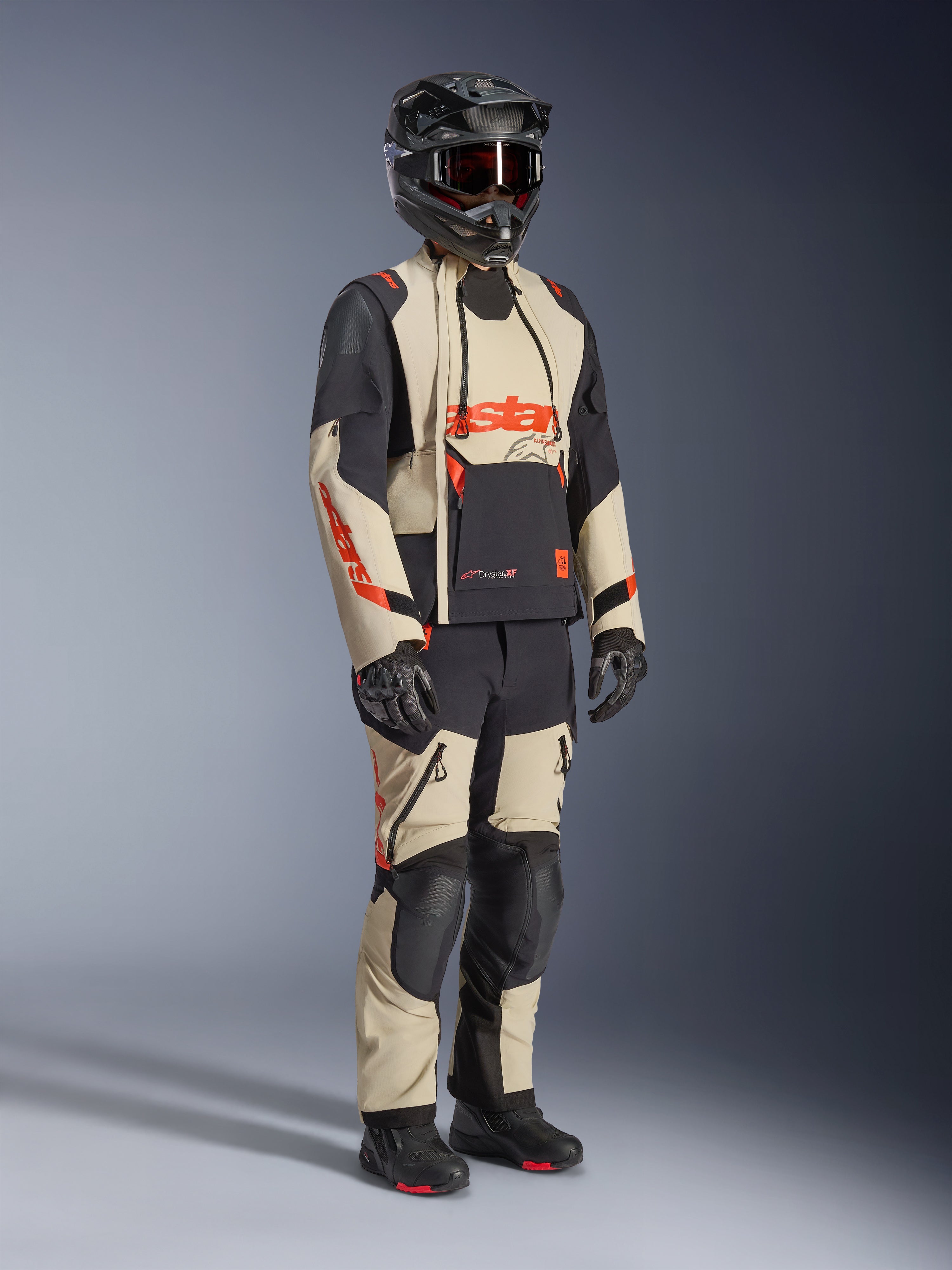 Alpinestars Halo Pro Drystar® XF lamineret jakke i Mastic Black, adventure-motorcykeljakke båret med matchende bukser, full-face hjelm, handsker og støvler, sandfarvede og sorte paneler med røde logoer, teknisk design til alle sæsoner