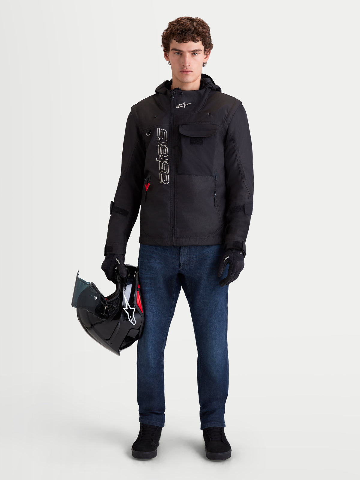 Alpinestars Morfex Parka Waterproof Jacket, herre-motorcykeltekstiljakke i sort, set forfra på model iført jeans og med en hjelm, der fremviser modulopbygget design og integreret hætte