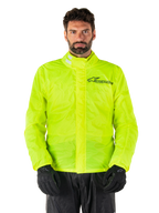 Alpinestars Hurricane Rain V2-jakke, motorcykelregnjakke, neongul, båret af model med sorte bukser og handsker, høj krave med reflekterende detaljer, front-stormklap med Alpinestars-logo, vandtæt udstyr med høj synlighed