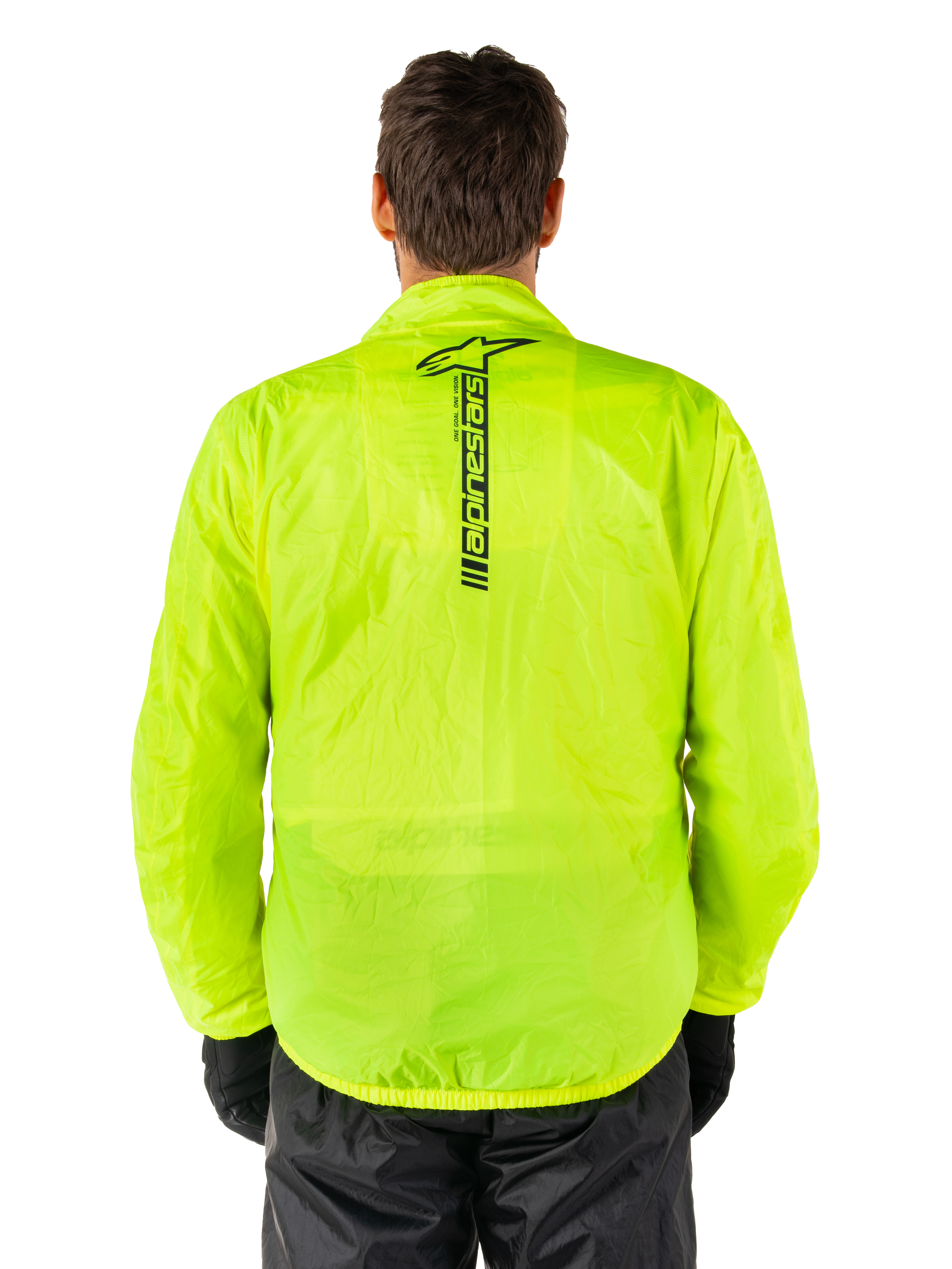 Alpinestars Hurricane Rain V2-jakke, regnjakke til motorcykel, Yellow Fluo, set bagfra viser lodret sort Alpinestars-logo midt på ryggen, let vandtæt materiale, båret med sorte kørebukser og handsker