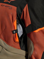 Alpinestars Andes V4 Drystar® jakke, Walnut Rust Black, nærbillede af direkte ventilationsåbning med mesh-foring, slidstærkt tekstilmateriale med orange detaljer, trykknap og Alpinestars-logodetalje
