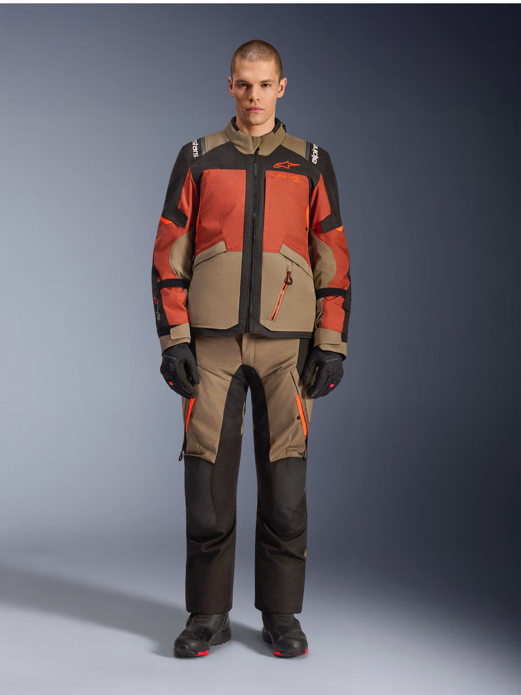 Alpinestars Andes V4 Drystar® jakke, adventure-motorcykeljakke, Walnut Rust Black, båret med matchende bukser og handsker, multi-tonalt design med rustorange og valnøddebrune paneler, holdbart tekstiludstyr til terrænkørsel