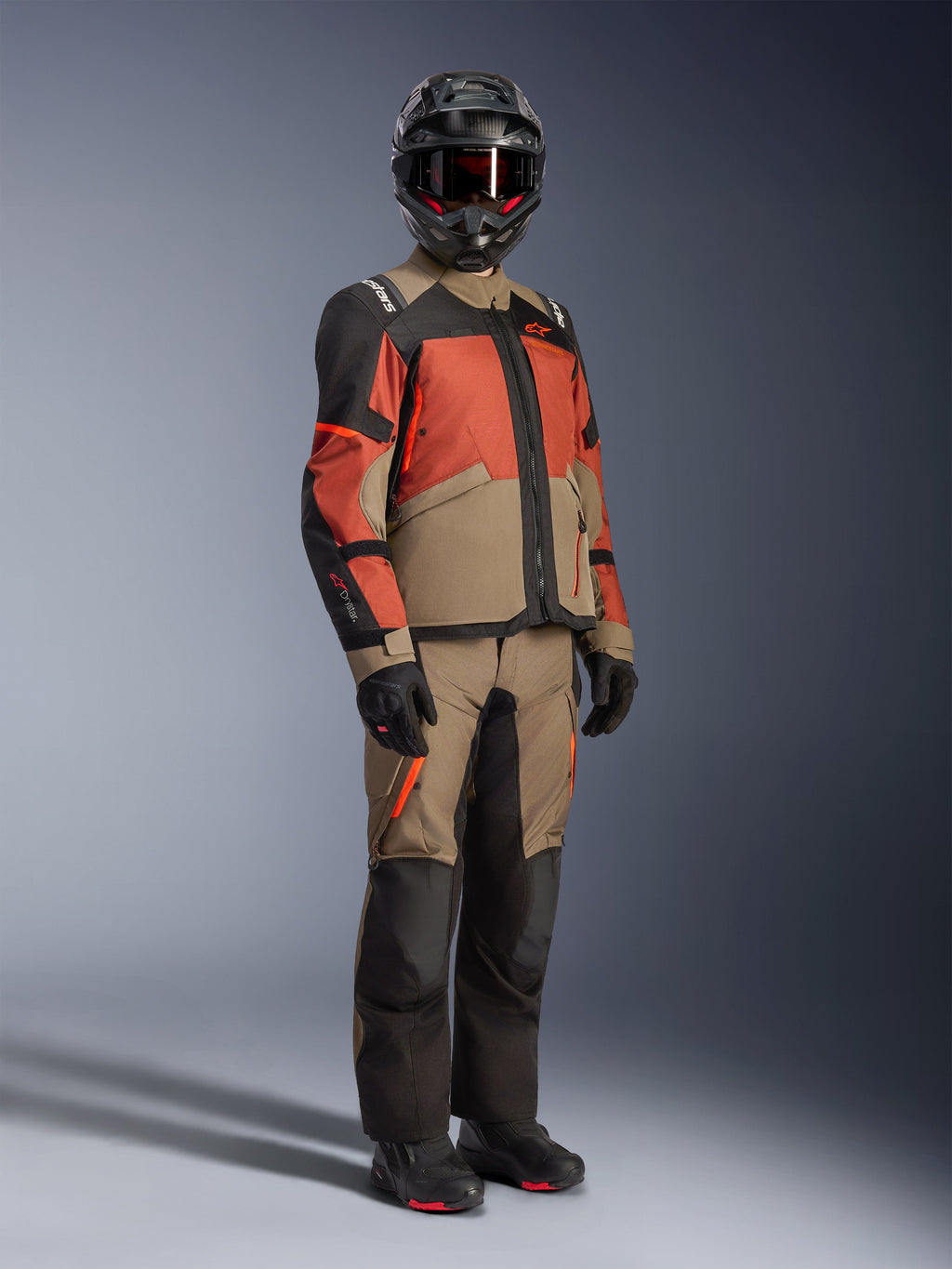Alpinestars Andes V4 Drystar® jakke i Walnut Rust Black, adventure touring-motorcykeljakke, båret med matchende walnut og sorte bukser, sort hjelm og kørestøvler, med en slidstærk tekstilkonstruktion med flerfarvede paneler til kørsel i al slags vejr