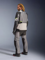 Alpinestars Andes V4 Drystar® jakke, mørkegrå, isgrå, sort og gul fluo, kører set bagfra iført matchende adventure touring-bukser og støvler, med forstærkede grå tekstilpaneler, neon gule detaljer og Alpinestars-branding, motorcykeludstyr til al slags vejr.
