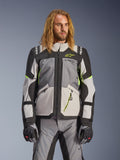 Alpinestars Andes V4 Drystar-jakke, adventure touring-motorcykeljakke, mørkegrå og isgrå med neongule detaljer, båret af en model med matchende bukser og handsker, tekstildesign med flere lommer til kørsel i al slags vejr