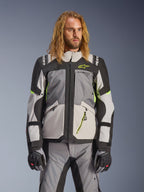 Alpinestars Andes V4 Drystar-jakke, adventure touring-motorcykeljakke, mørkegrå og isgrå med neongule detaljer, båret af en model med matchende bukser og handsker, tekstildesign med flere lommer til kørsel i al slags vejr