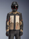 Alpinestars Andes V4 Drystar® Jakke, Walnut Mastic Black, adventure-touringjakke med valnøddebrune og mastic-cremefarvede paneler, sorte ærmer og klare orange detaljer, båret med en sort motorcykelhjelm, mørke goggles og sorte handsker