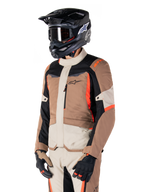 Alpinestars ST-1 vandtæt jakke, adventure touring-jakke, mørk khaki, sand, sort og rød fluo, bæres af en kører med en sort motocrosshjelm og briller, design med flere paneler, cargo-lommer og Alpinestars-branding på brystet