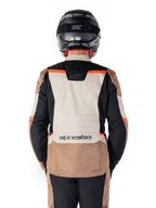 Alpinestars ST-1 Vandtæt Jakke, Dark Khaki Sand Black Red Fluo, set bagfra, adventure touring motorcykeljakke med et stort sandfarvet rygpanel, sorte ærmer og fluorescerende røde detaljer, vist på en kører med en sort hjelm.