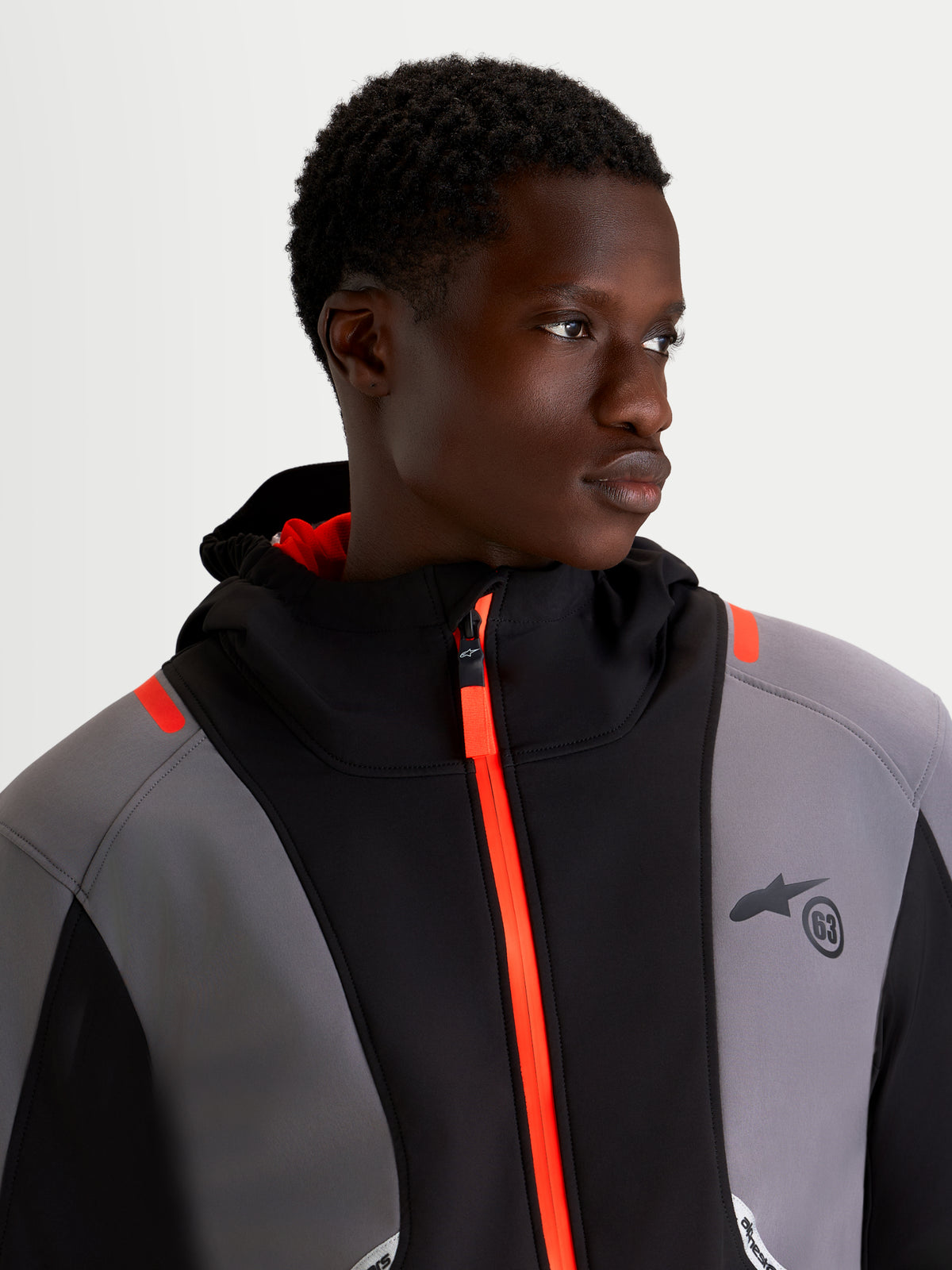 Alpinestars C 5 Drystar jakke, herre-urban-motorcykeltekstiljakke i sort og mørkegrå, tæt udsnit af en model iført den vandtætte softshell-jakke med skrigorange lynlås foran og integreret hætte