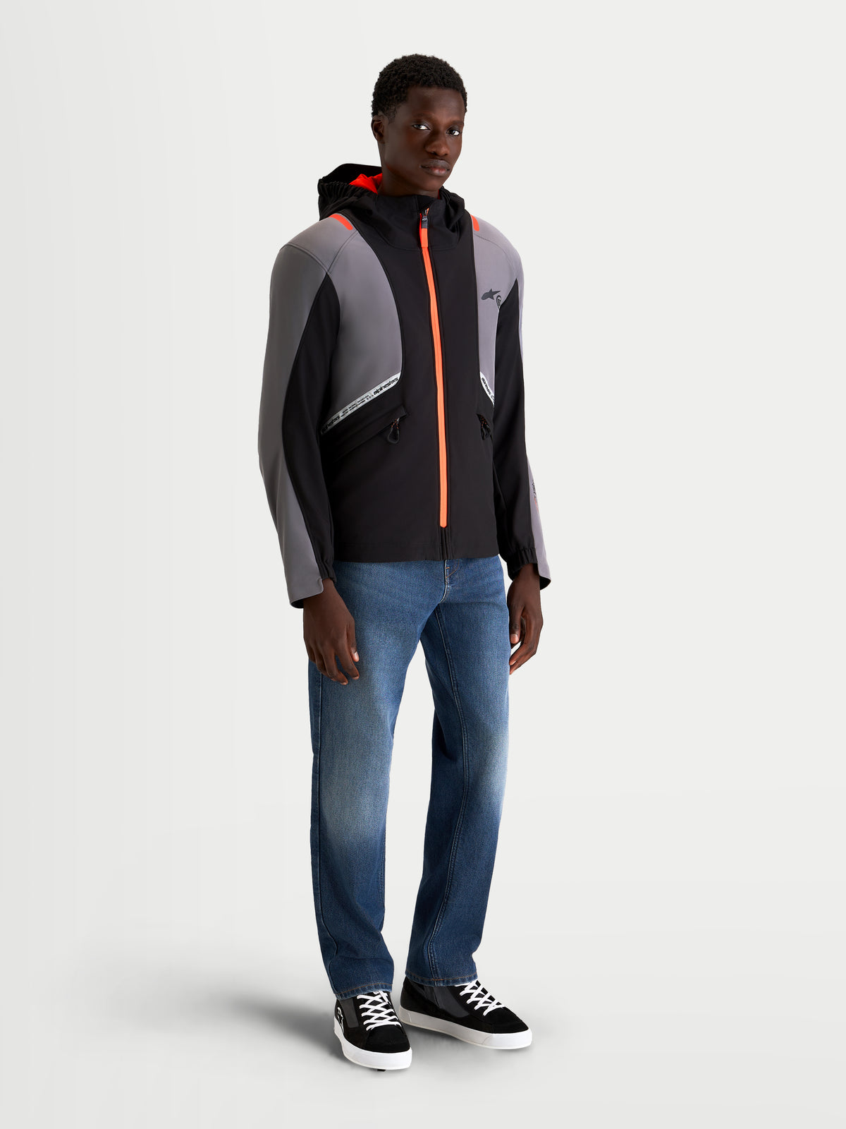 Alpinestars C-5 Drystar jakke, herre urban motorcykeltekstiljakke i sort og mørkegrå, med integreret hætte, vandtæt konstruktion og lyse orange lynlådetaljer, båret af en model