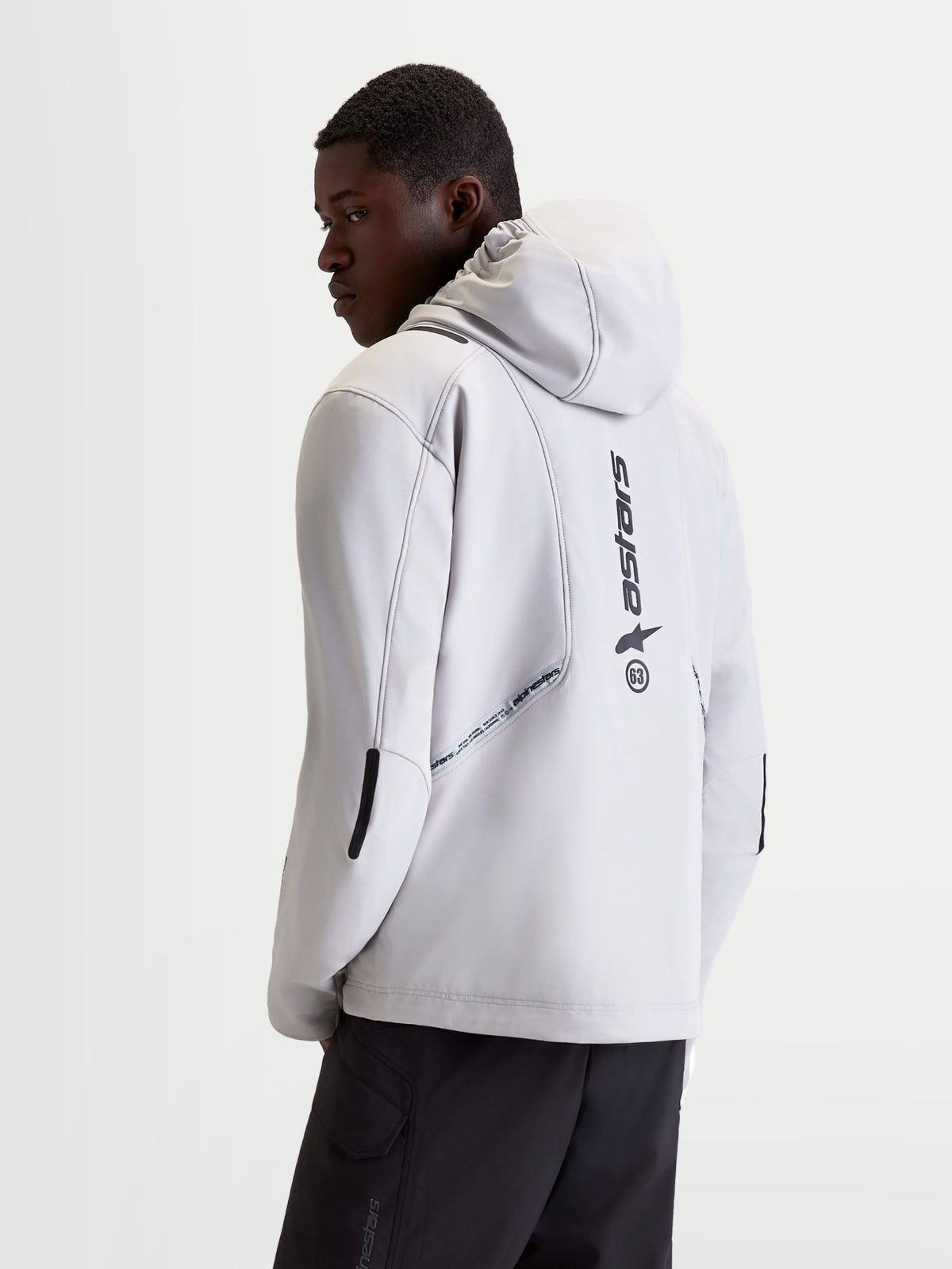 Alpinestars C 5 Drystar jakke, herre-urban-motorcykeltekstiljakke i lys grå og sort, set bagfra på en model der viser integreret hætte, softshell-konstruktion og lodrette logo-detaljer på ryggen