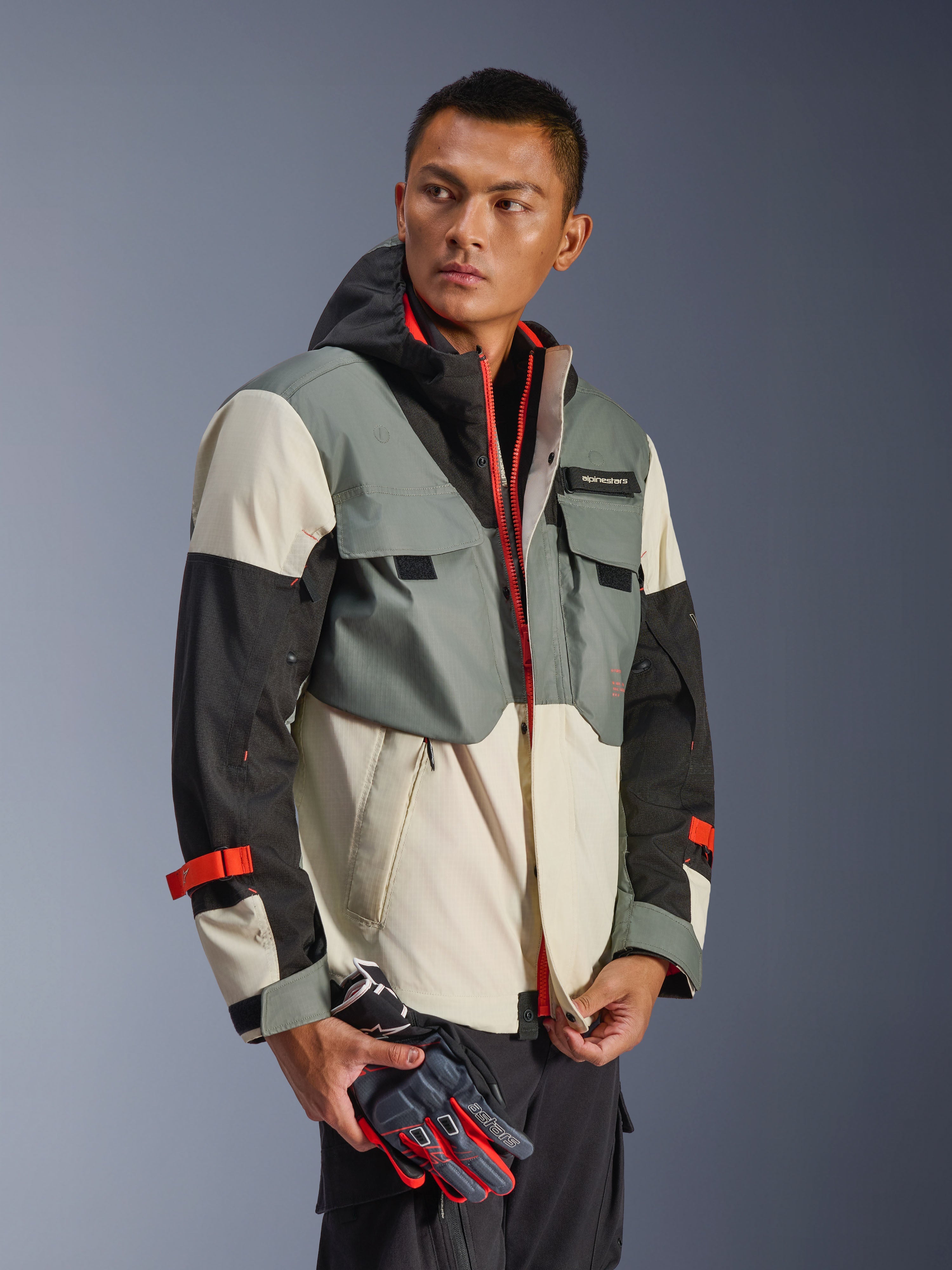 Alpinestars Mospher Waterproof Jacket i Fur Gray Black Ice, multi-panel tekstilparka med grå, sorte og råhvide sektioner, klare røde lynlås- og remdetaljer, taktisk inspireret design med hætte og funktionelle lommer, båret af model med motorcykelhandsker