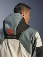 Alpinestars Mospher vandtæt jakke, Fur Gray Black Ice, nærbillede bagfra af hætteforankringssystemet med en orange trykknap-strop, MO.ST.EQ. Moto Streetwear Equipment branding, holdbar ripstop-tekstilkonstruktion