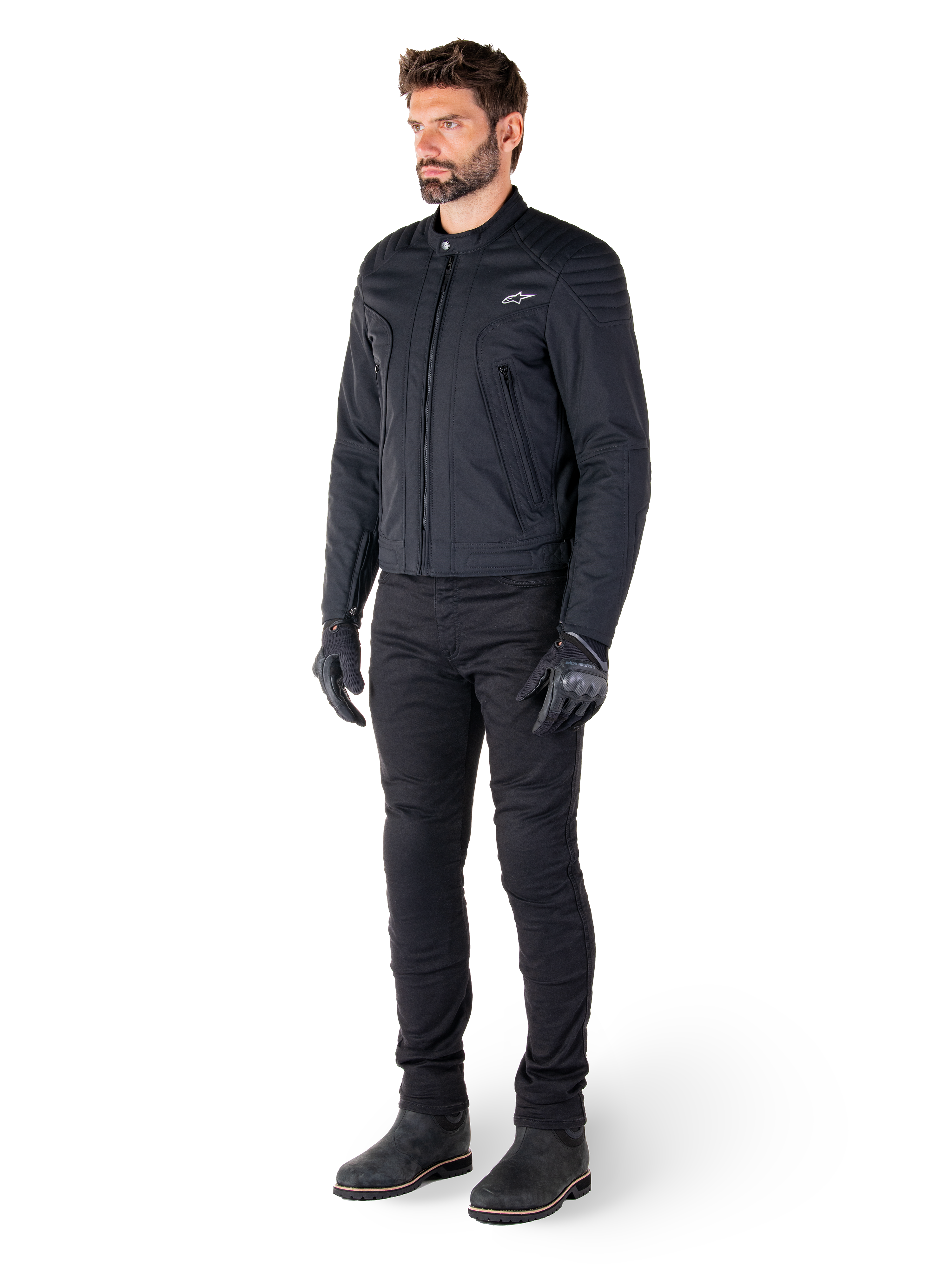 Mandlig kører iført Alpinestars Clayton WR-jakken, sort urban motorcykeljakke, slim-fit design med quiltede skulderdetaljer og mat finish, kombineret med sorte tekniske kørebukser og handsker.