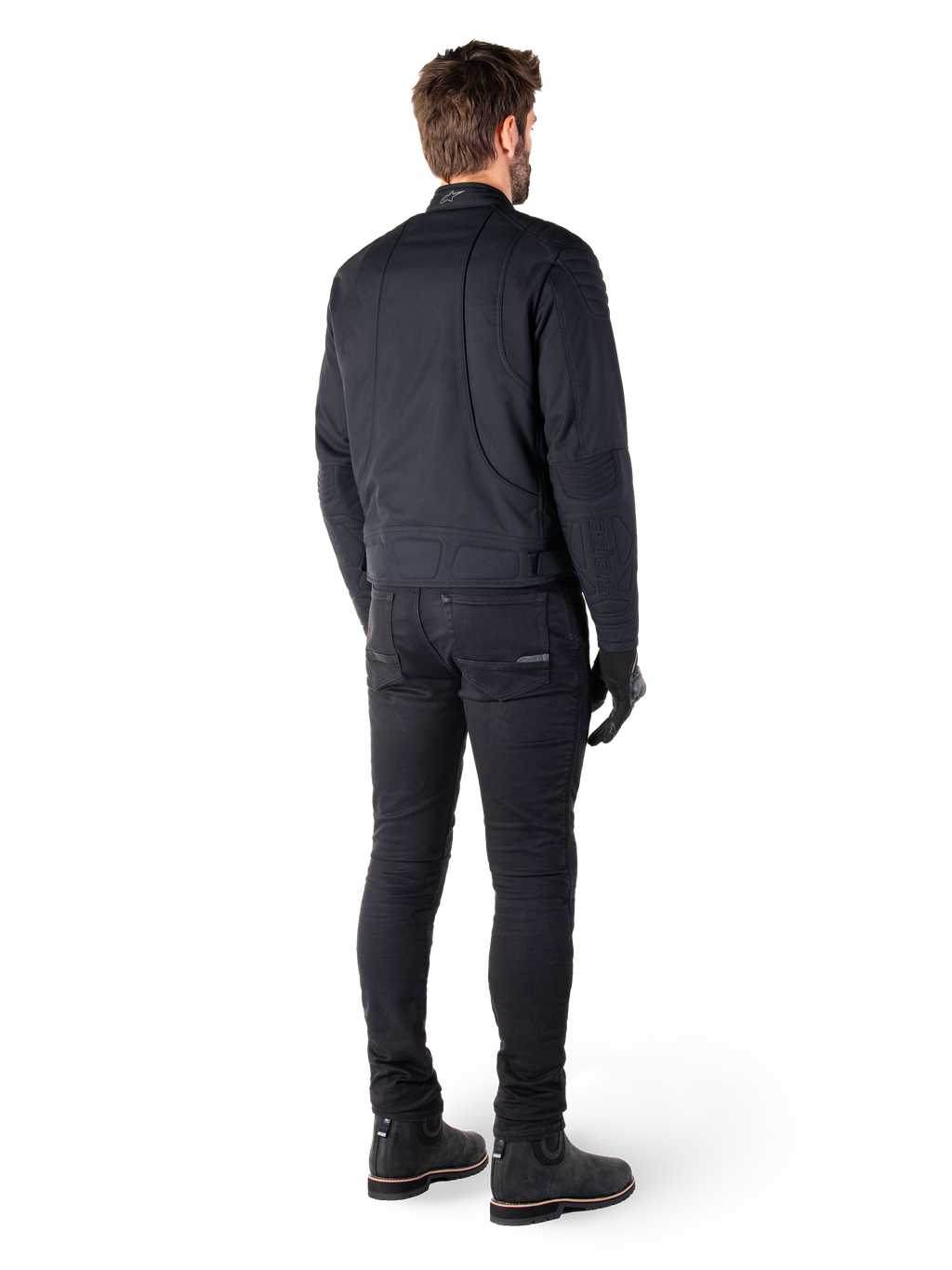 Alpinestars Clayton WR-jakke i sort, set bagfra af en kører, med quiltede albue- og skulderpaneler, ergonomiske buede syninger, reflekterende detaljer på kraven, sorte kørebukser og støvler, urbant motorcykel-look.