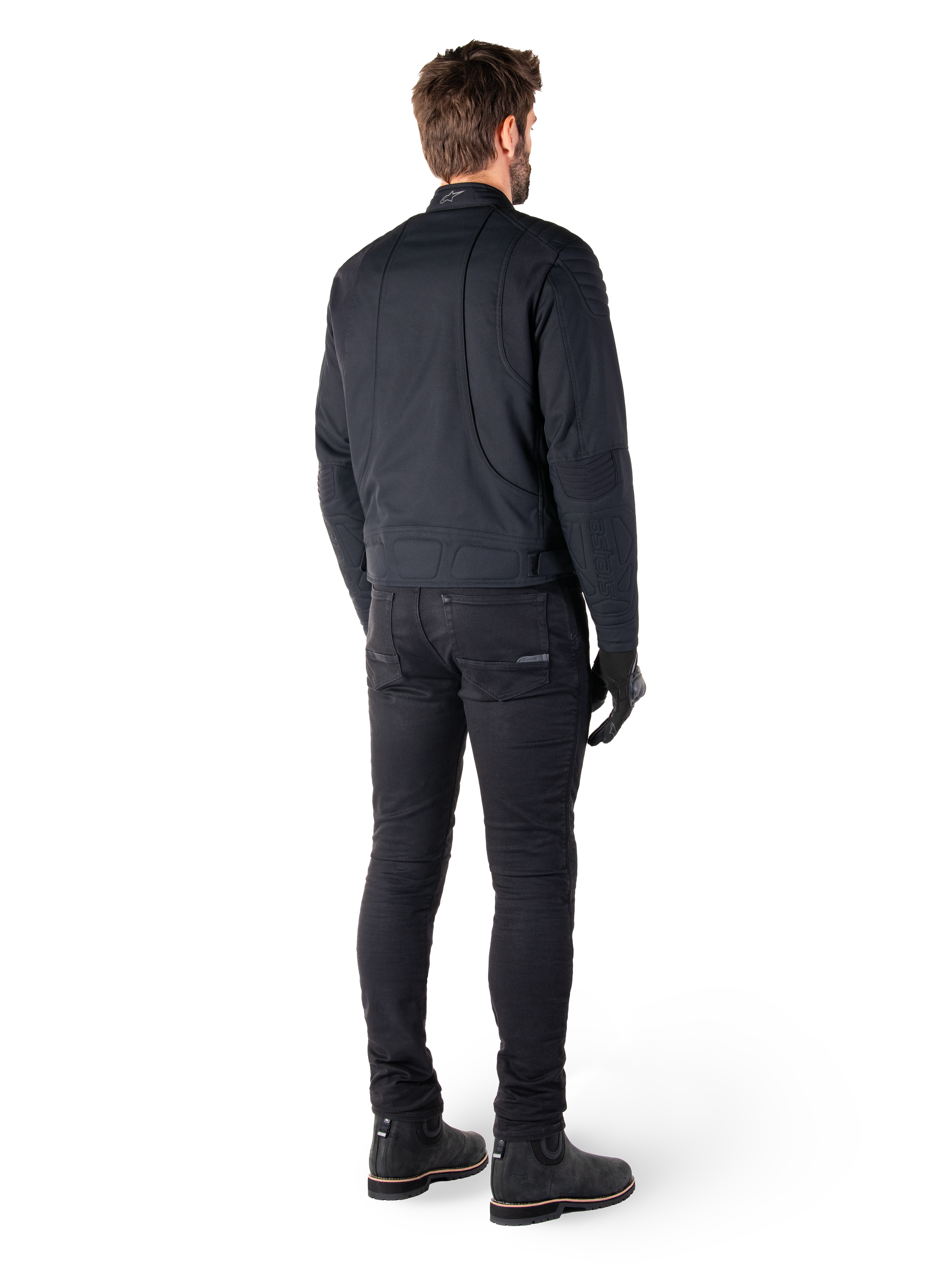 Alpinestars Clayton WR-jakke i sort, set bagfra af en kører, med quiltede albue- og skulderpaneler, ergonomiske buede syninger, reflekterende detaljer på kraven, sorte kørebukser og støvler, urbant motorcykel-look.