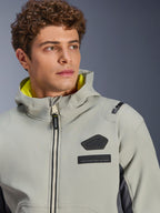 Alpinestars Moblast vandtæt jakke, Iron Gray Dark Sage, nærbillede af mandlig model iført jakken, med sort Alpinestars-logo og MO.ST.EQ. brystmærker, lysegult hættefor og et moderne teknisk design.
