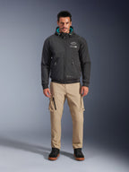 Alpinestars Moblast Waterproof Jacket, sort urban motorcykel-hættetrøje med blågrønt indvendigt hættefor, båret med sandfarvede cargobukser og sorte high-top støvler, moderne køreudstyr til alle årstider