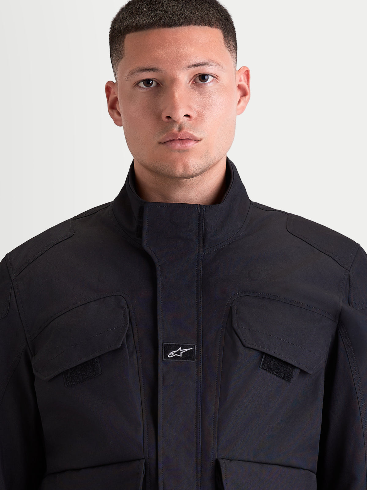 Alpinestars Altan Drystar Jacket, men's urban contemporary motorcycle jacket in black, front close-up view showing matte polyfabric construction, integrated warm collar, and chest cargo pockets worn by a model.