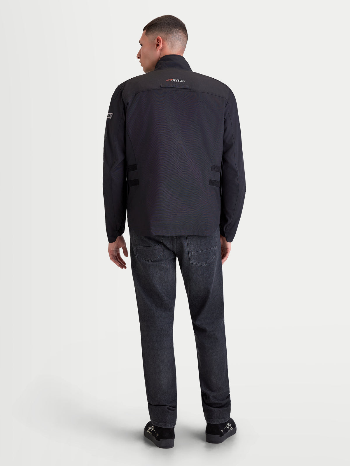 Alpinestars Altan Drystar Jacket, men's urban contemporary motorcycle textile jacket in black, rear view on a model showing waterproof construction, integrated warm collar, and Drystar branding.