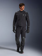 Mandlig model iført Alpinestars Andes Pro Drystar® XF jakke, sort og mørkegrå adventure-motorcykeljakke, kombineret med matchende tekniske bukser og handsker, med flere lommer og 'Terra'-branding på brystet.