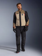 Mandlig model iført Alpinestars Andes Pro Drystar® XF-jakke i Walnut Aluminum, tan- og sort adventure-touringjakke med røde detaljer, kombineret med sorte motorcykelbukser, handsker og støvler, studiefoto i fuld figur af beskyttende køreudstyr.