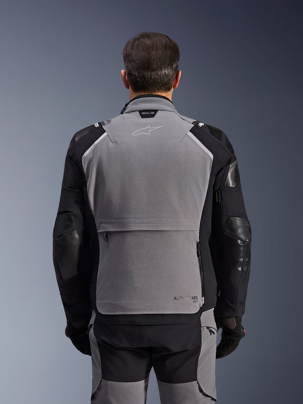 Alpinestars Andes Pro Drystar® XF-jakke, set bagfra, mørkegrå og sort, adventure touring-jakke med en stor opbevaringslomme bagpå, Tech-Air® Ready-branding på kraven og forstærkede albuepaneler.