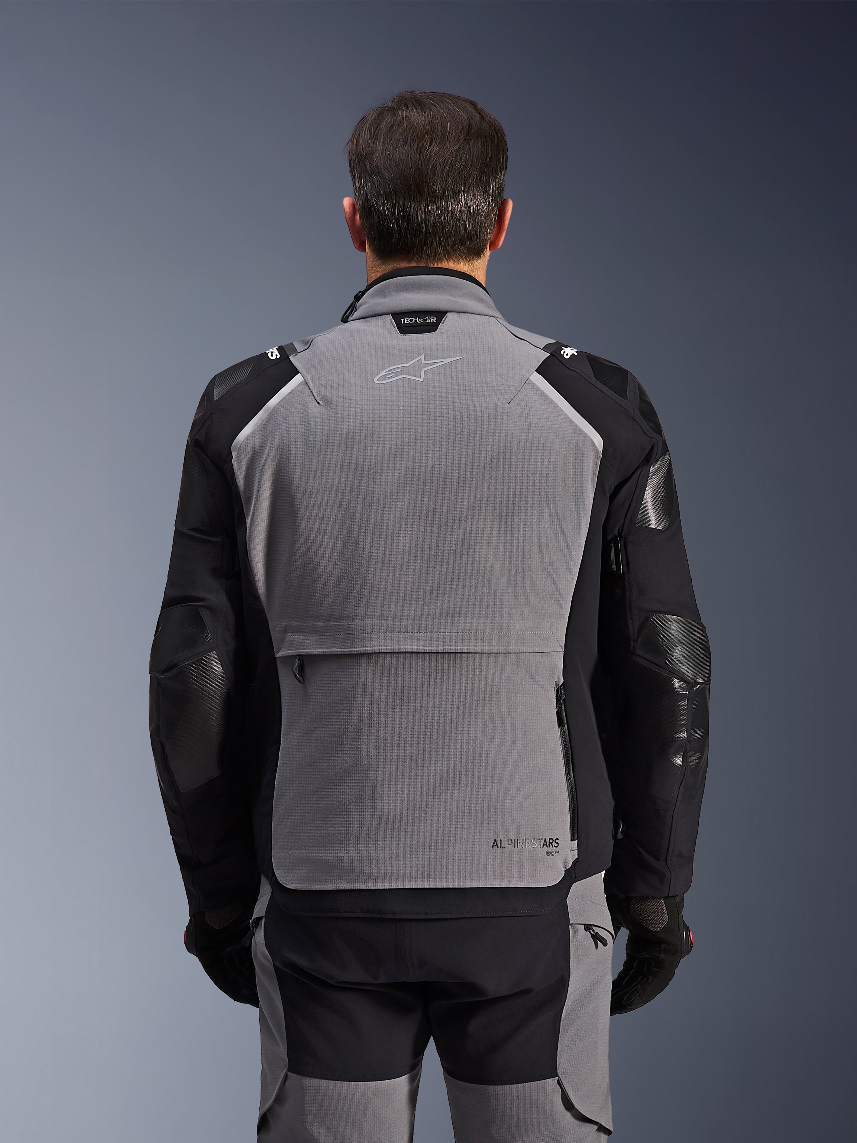 Alpinestars Andes Pro Drystar® XF-jakke, set bagfra, mørkegrå og sort, adventure touring-jakke med en stor opbevaringslomme bagpå, Tech-Air® Ready-branding på kraven og forstærkede albuepaneler.