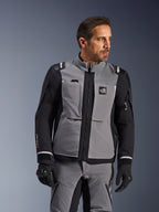 Alpinestars Andes Pro Drystar® XF-jakke i mørkegrå og sort, adventure-køreudstyr, båret af en mand med matchende grå bukser og sorte handsker, med en 3-lags lamineret skal, praktiske lommer og 'Terra'-logo på brystet