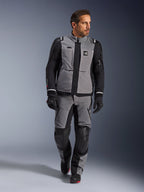 Mandlig model iført Alpinestars Andes Pro Drystar® XF-jakke i mørkegrå og sort, adventure motorcykel-køredragt med matchende bukser og handsker, med en teknisk tekstilskal med 'All Terra'-branding, komplet udstyr til langdistance adventure-touring