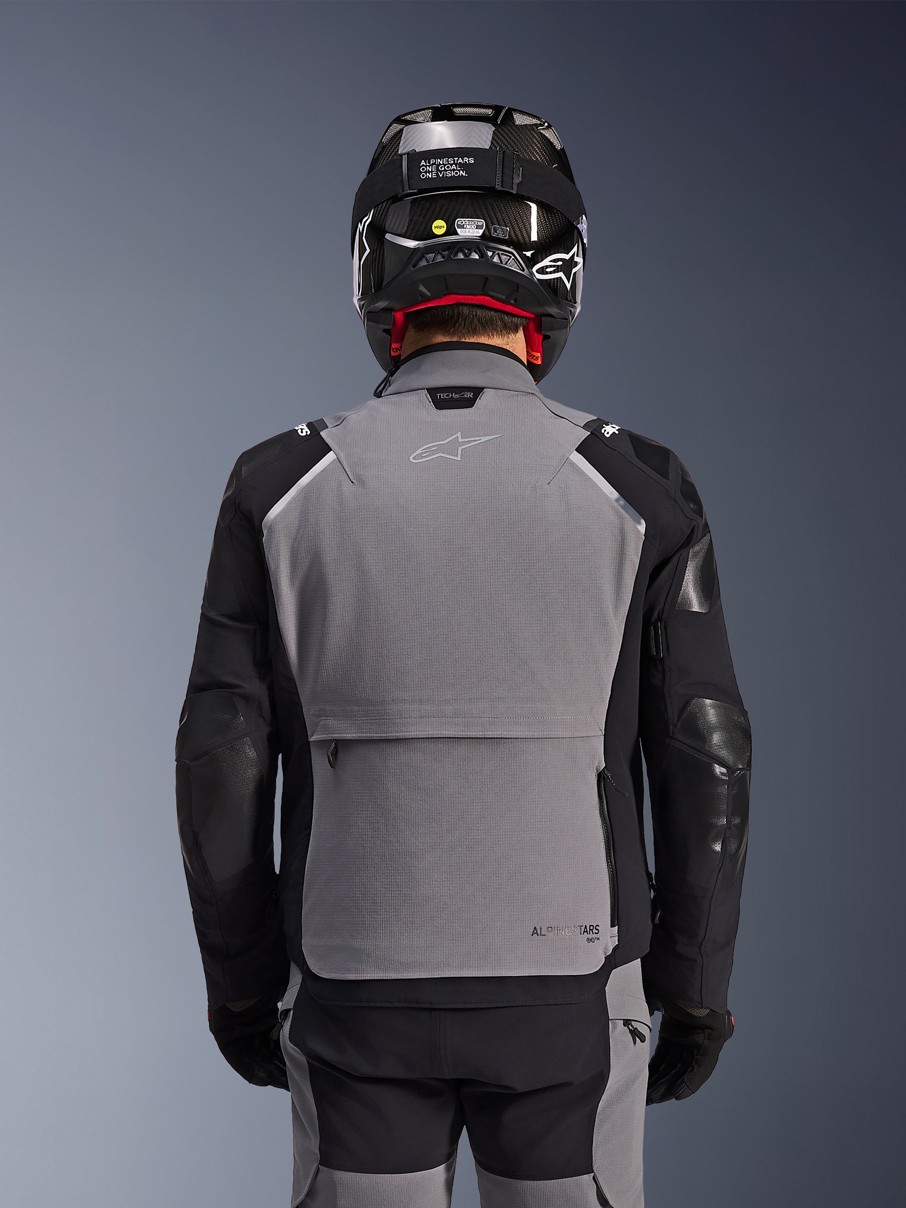 Alpinestars Andes Pro Drystar® XF jakke, mørkegrå og sort, set bagfra med stor baglomme og Tech-Air branding, båret af en kører med sort hjelm og matchende kørebukser, professionelt adventure touring-udstyr