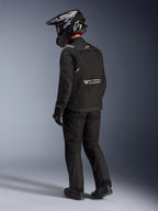 Alpinestars Cusco Drystar®-jakke i sort, set bagfra fra siden af en kører iført et komplet adventure touring-sæt, inklusive matchende sorte bukser og handsker, sort adventure-hjelm, tekstilkonstruktion med reflekterende branding på ryggen