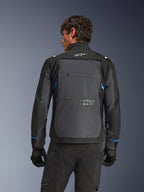 Alpinestars Cusco Drystar®-jakke, motorcykeljakke, sort og mørkegrå, set bagfra på en model, viser stort gråt rygpanel, hvidt Alpinestars-logo og blå detaljer på ærmerne