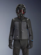 Alpinestars Cusco Drystar® jakke, adventure touring-jakke til motorcykel, sort og mørkegrå, båret med matchende sorte tekniske bukser og en dual-sport-hjelm, med et tofarvet design med ripstop-paneler og Alpinestars-branding