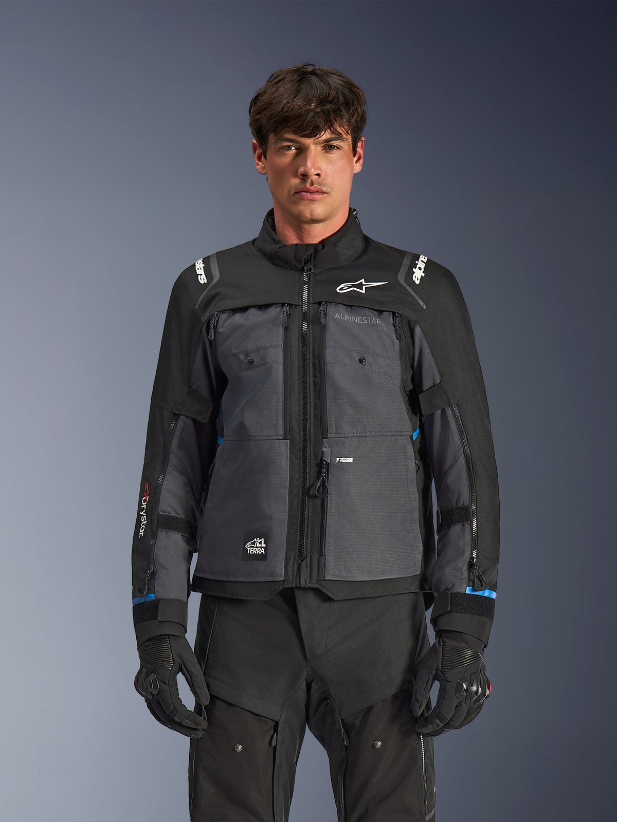 Alpinestars Cusco Drystar® jakke, motorcykel touring-jakke, sort og mørkegrå, set forfra på model, med Alpinestars-logoer på bryst og skuldre, Drystar®-branding på ærmet, teknisk multilomme-design med ventilationslynlåse, kombineret med sort køreudstyr
