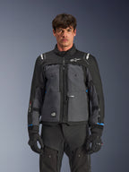 Alpinestars Cusco Drystar® jakke, motorcykel touring-jakke, sort og mørkegrå, set forfra på model, med Alpinestars-logoer på bryst og skuldre, Drystar®-branding på ærmet, teknisk multilomme-design med ventilationslynlåse, kombineret med sort køreudstyr