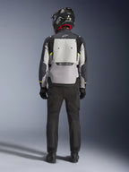Motorcyklist set bagfra iført Alpinestars Cusco Drystar®-jakke i Ice Gray, Mid Gray og Deep Gray, med et stort ventilationspanel på ryggen og Alpinestars-branding, kombineret med sorte kørebukser og en sort hjelm, adventure touring-motorcykelbeklædning