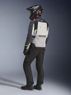Alpinestars Cusco Drystar® jakke i Ice Gray, Mid Gray og Deep Gray, set bagfra på en kører. Har fluorescerende gule detaljer, et stort ventilationspanel på ryggen med branding og en slidstærk tekstilkonstruktion. Vist sammen med sorte motorcykelbukser og en adventure-hjelm for et komplet touring-look.