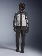 Alpinestars Cusco Drystar® jakke, Ice Gray Mid Gray Deep Gray, adventure-motorcykeljakke båret med sorte kørebukser, sorte handsker og en sort hjelm med goggles, med farveopdelte grå paneler og tekniske detaljer til vej- og adventure-touring