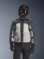 Alpinestars Cusco Drystar® jakke, adventure touring-jakke, Ice Gray, Mid Gray og Deep Gray, med grå paneler i flere nuancer, brystventilation med lynlås og Alpinestars-branding, båret af en kører med sort hjelm og goggles.