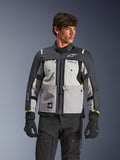 Alpinestars Cusco Drystar® Jakke, adventure touring motorcykeljakke, Ice Gray, Mid Gray og Deep Gray, båret af en model med sorte bukser og handsker, teknisk tekstildesign med flere paneler, brystlommer, 'Drystar'-branding på ærmet og subtile neongule detaljer ved manchetterne.